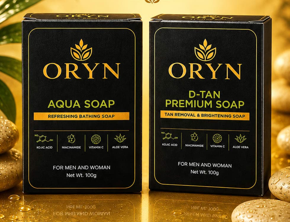 ORYN Aqua Soap and D-TAN Premium Soap cartons side by side on wet gold stone.